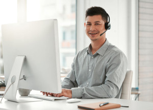 He's got a passion for helping people. a young male call center agent using a computer in an office at work.